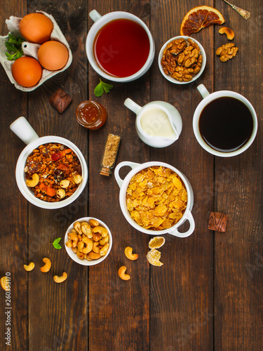cornflakes, coffee, bread, butter, eggs, jam and other ingredients for breakfast on a dark background. Top view with copy space