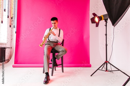 Photos Saxophonist in classic clothes playing the soprano saxophone sitting on a chair
