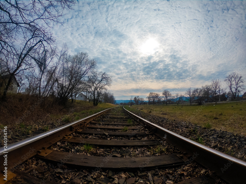 Fototapeta premium Rails in the village and sunset with clouds