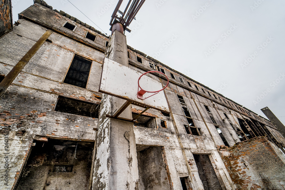 Close-up of almost abandoned building outdoors. Ruined plant building with damaged brick walls and metal structures without windows and doors. Close-up of almost abandoned building outdoors. Ruined plant building with damaged brick walls and metal structures without windows and doors.