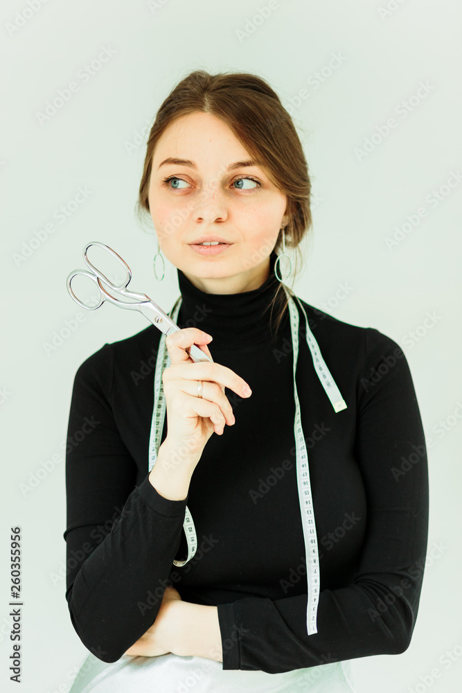 smiling cute seamstress holding scissors and looking at camera smiling cute seamstress holding scissors and looking at camera