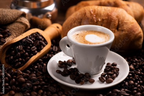 Cup of coffee surrounded by coffee beans