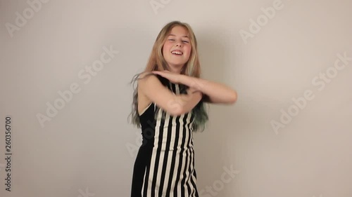 Cute girl is dancing macarena dance on gray background. photo