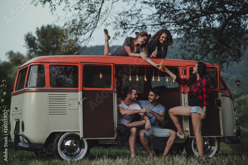 A group of friends at dusk outdoors on a roadtrip through countryside. photo