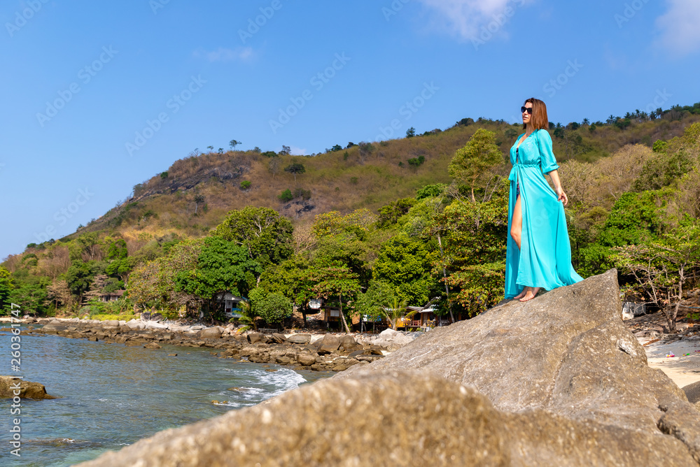 Fototapeta premium girl in a blue tunic on a stone sea beach