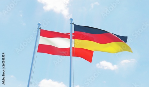 Austria and Germany, two flags waving against blue sky. 3d image