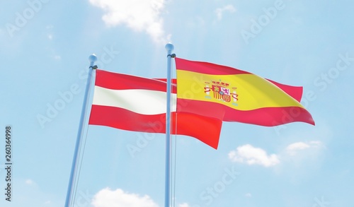 Austria and Spain, two flags waving against blue sky. 3d image
