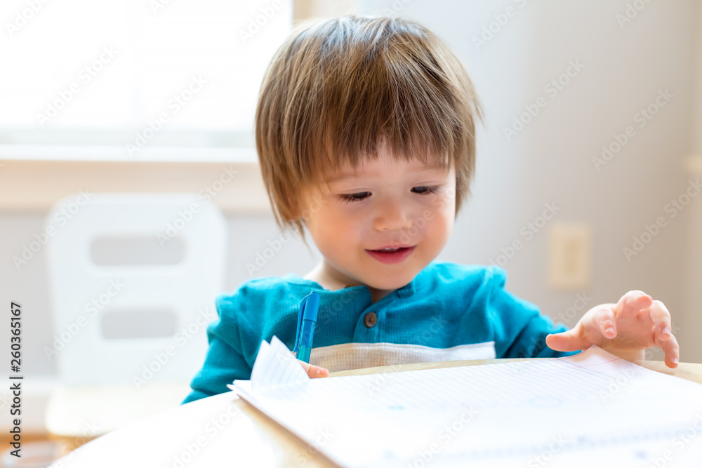 Happy toddler boy drawing at his desk Happy toddler boy drawing at his desk