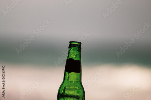 Empty 33cl bottle of beer close up, edited; sea view background. iconic image. photo