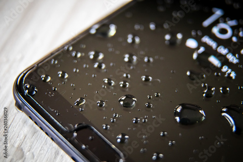 Front side of waterproof smartphone covered with drops of water