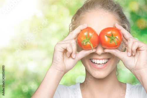 Beautiful laughing woman holding two ripe tomatoes