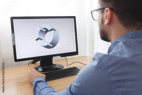 Engineer, Constructor, Designer in Glasses Working on a Personal Computer. He is Creating, Designing a New 3D Model of Mechanical Component in CAD Program. Freelance Work