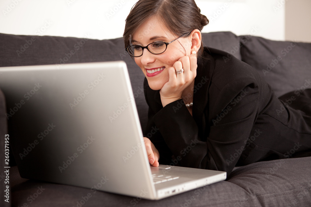 Businesswoman Working on Laptop Computer While Lying on Couch at Home Businesswoman Working on Laptop Computer While Lying on Couch at Home