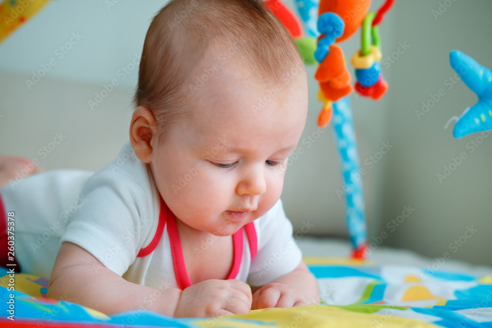 Adorable baby girl having fun with toys on colorful play mat Adorable baby girl having fun with toys on colorful play mat