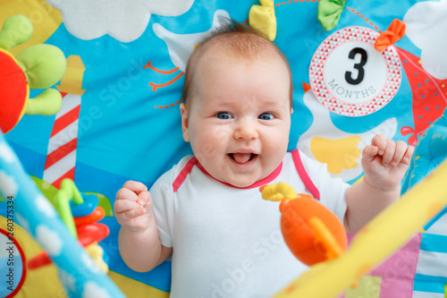 Adorable baby girl having fun with toys on colorful play mat