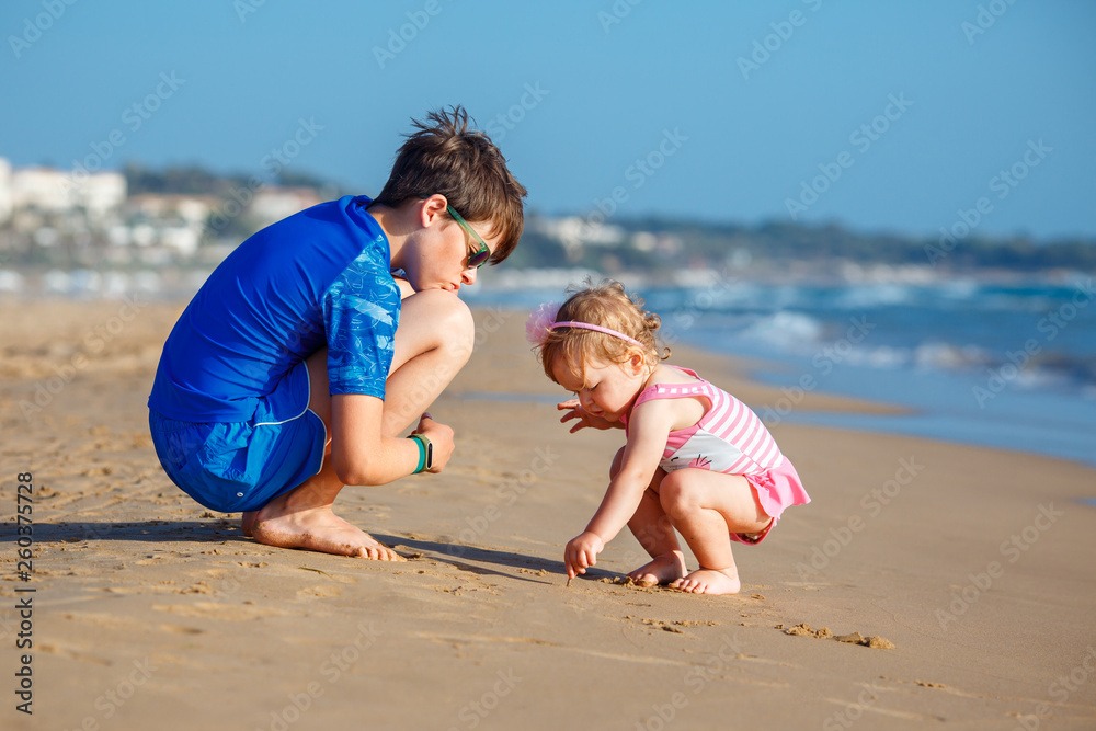 Kids playing on a beach. Two children dig sand at the sea shore. Family vacation on a tropical resort. Traveling with young child. Kids playing on a beach. Two children dig sand at the sea shore. Family vacation on a tropical resort. Traveling with young child.