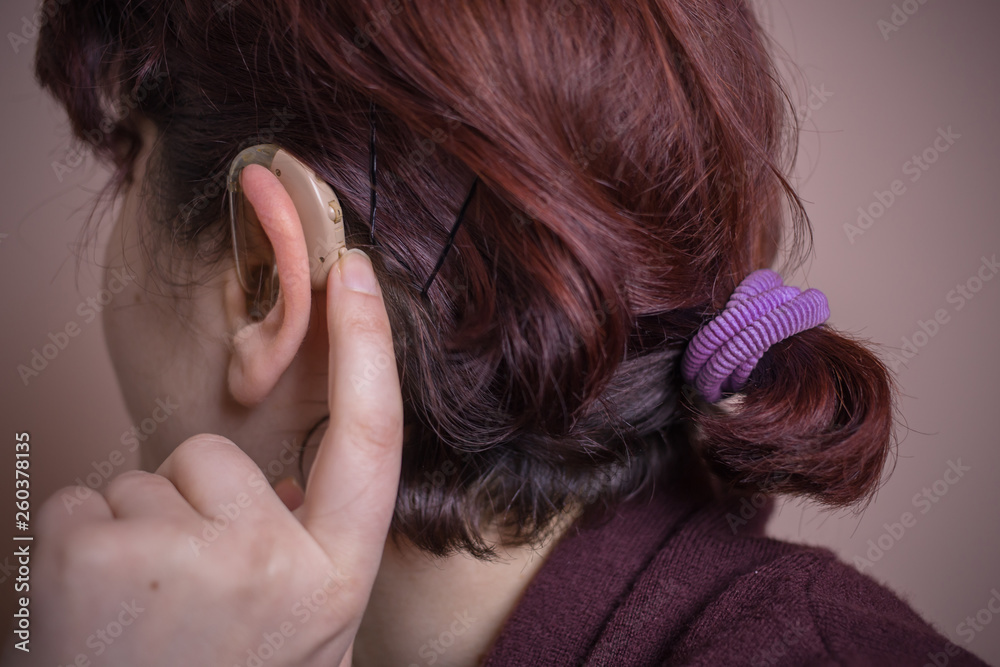 Close-up photo of a woman with hearing aid behind her ear. Sensory disability. Hearing disability Close-up photo of a woman with hearing aid behind her ear. Sensory disability. Hearing disability