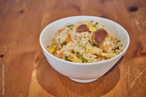 A Bowl of Chinese Fried Rice with Pork Sausages and vegetables.