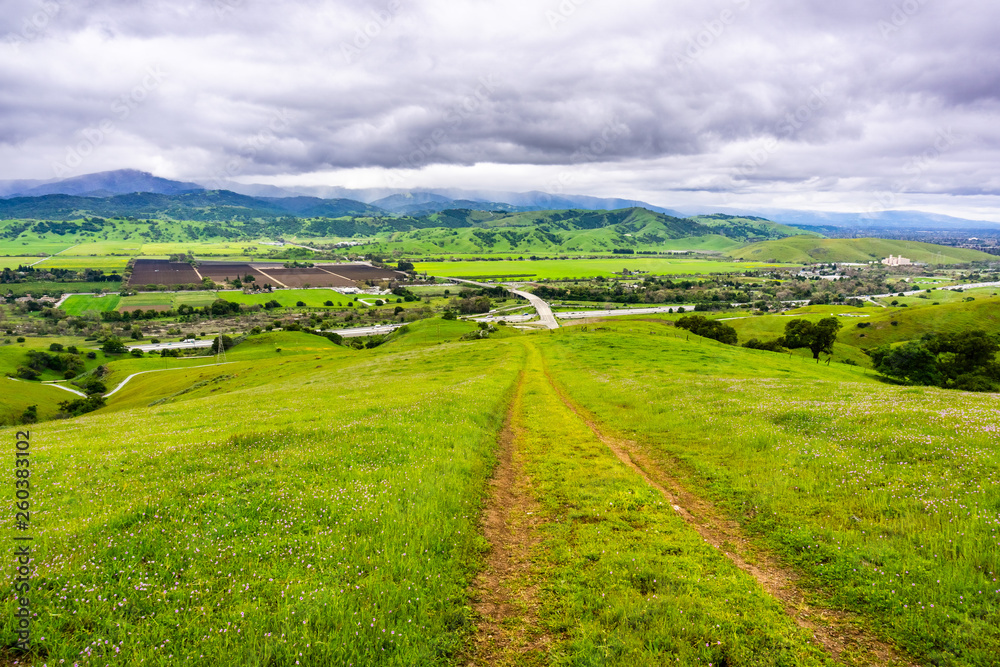 Hiking trail descending into the valley; Aerial view of agricultural fields and mountains in the  background, south San Francisco bay, San Jose, California