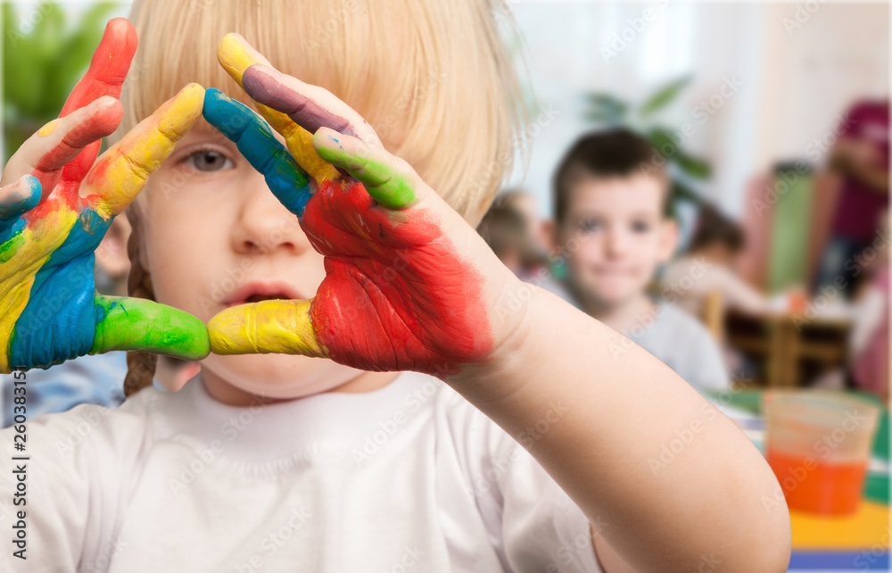 Obraz premium Cute little girl with colorful painted hands on class background