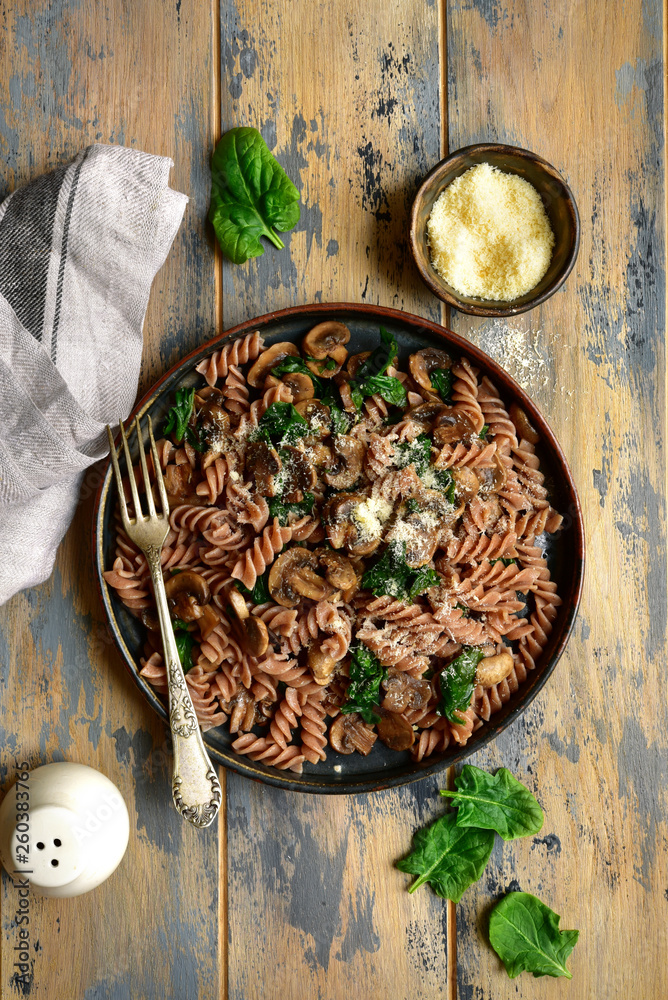 Whole wheat fusilli pasta with mushroom and spinach.Top view with copy space. Whole wheat fusilli pasta with mushroom and spinach.Top view with copy space.