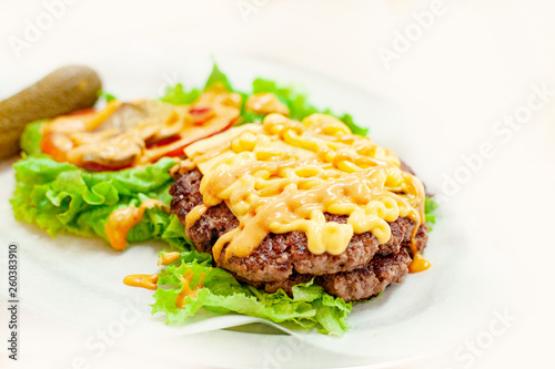 Cheeseburger Or Hamburger With Beef Cutlet, Tomatoes And Cheese Slices, Seasoned With Sauce And Green Salad Without Bread On White Background.