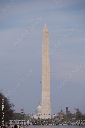 Washington Monument in DC during the annual Cherry Blossom Festival and the Kite festival reflecting in the pool, with the Capitol building in the background