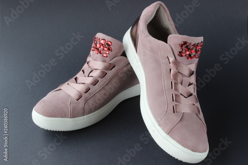 Pink sneakers with jewelry stones on black background