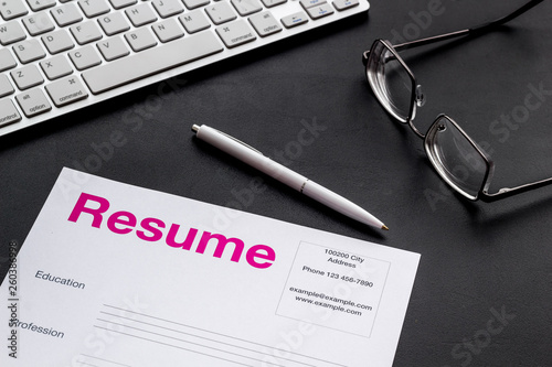 Review resumes of applicants set with keyboard and glasses black work desk background