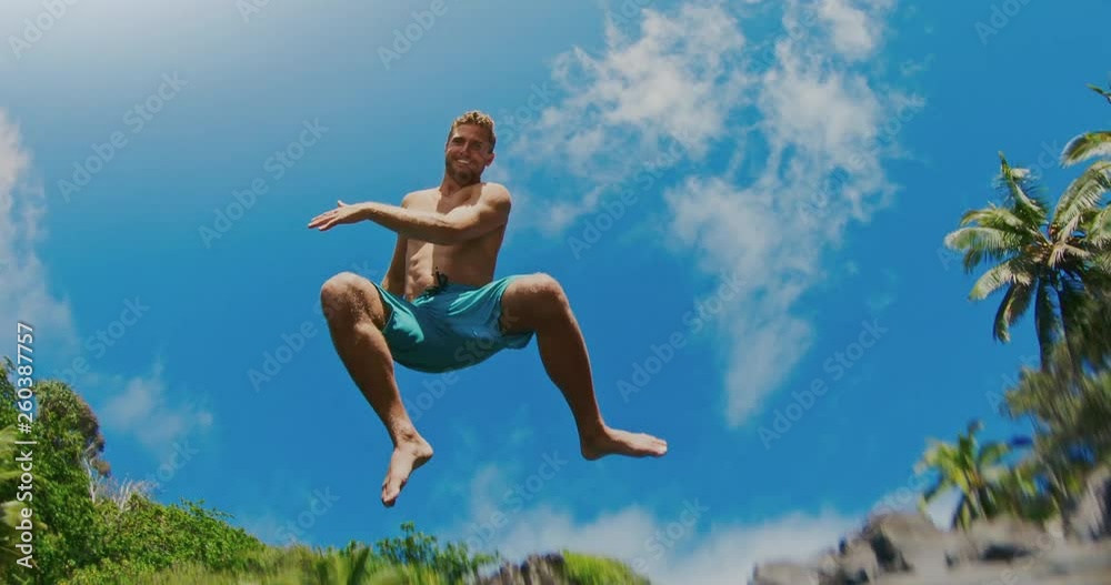 Action camera shot of young man jumping into pristine blue water