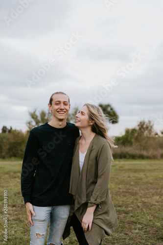 Young Couple in Love Running in a Big Open Outdoor Field in the Spring Holding Hands and Laughing