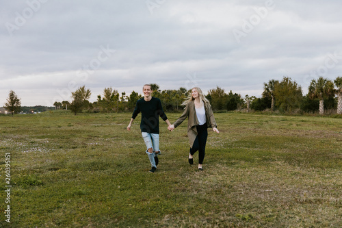 Young Couple in Love Running in a Big Open Outdoor Field in the Spring Holding Hands and Laughing © MeganMahoneyPhotos