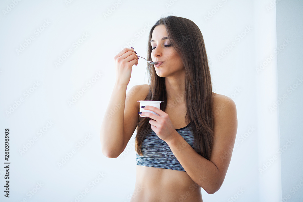 Diet. Beautiful young woman eating yogurt in the kitchen at home Diet. Beautiful young woman eating yogurt in the kitchen at home