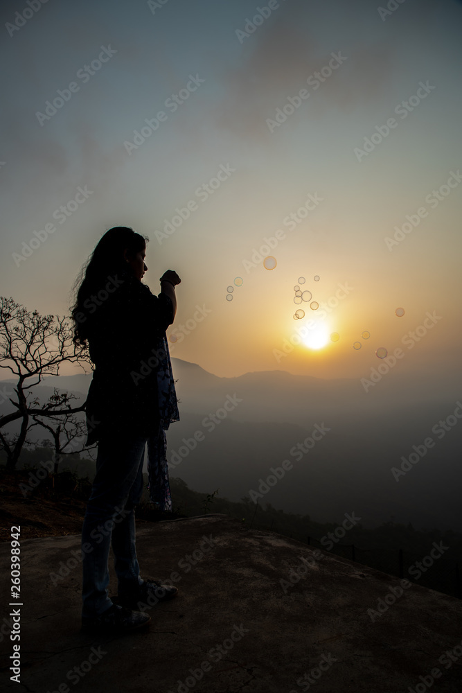 Silthouse of a girl playing during sunrise at Bisle Ghat, KA India