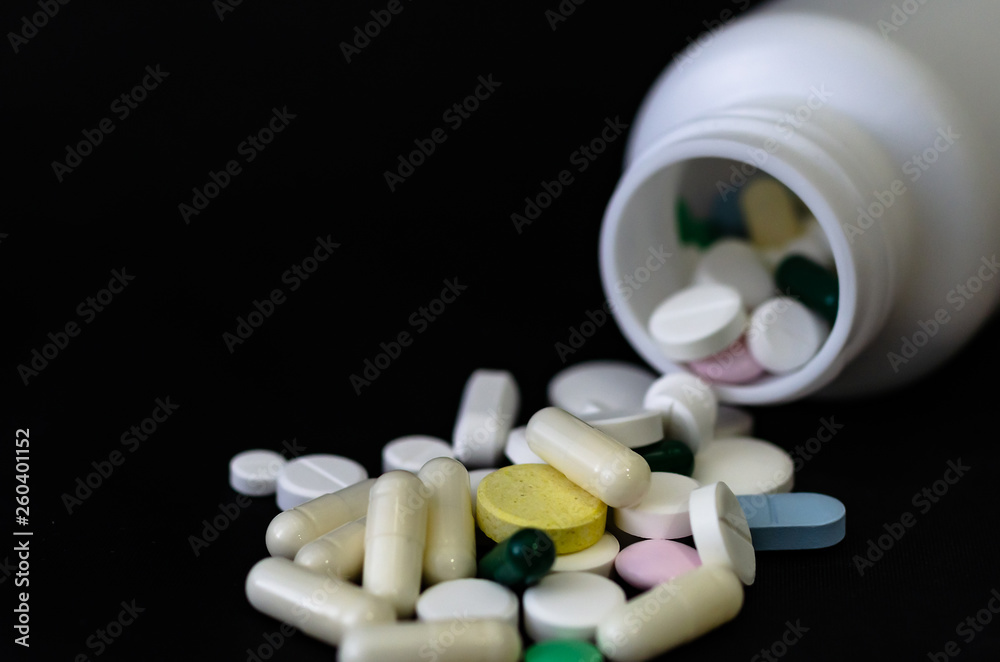 Medicinal tablets poured out of the jar on a black background. Medicinal tablets poured out of the jar on a black background.