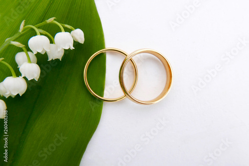 Gold wedding rings on wood with may flowers. 