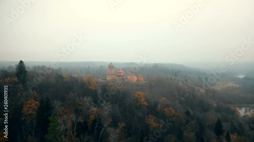 Drone flying towards ancient Turaidas castle and museum in Sigulda national park reserve, autumn foggy forest in Latvia. photo