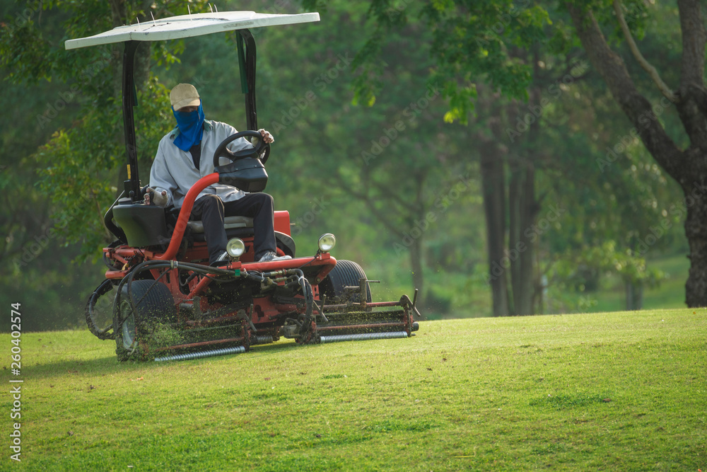 Workers taking care of the field are driving a mower. Workers taking care of the field are driving a mower.