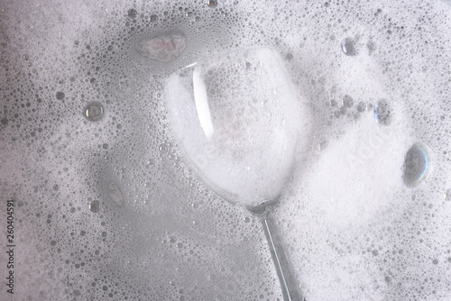 Valokuva A dishpan with a single wine glass immersed in soapy water