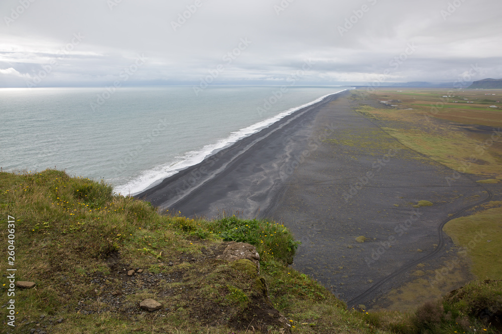 High cliff above the sea shore with black lava sand