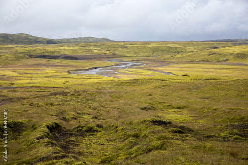 Endless lava fields covered with green moss crosses a small river, fancifully curving