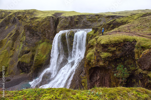 The girl stands on the edge of the gorge at the waterfall Fagrifoss