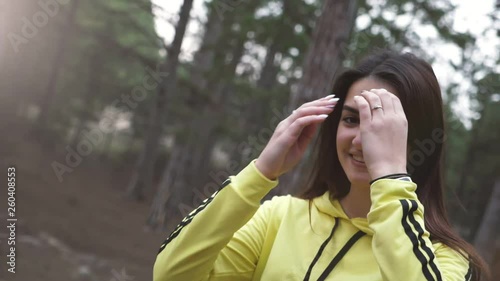 Gorgeous girl smiling and smartening up in a pine forest in spring in slo-mo   photo