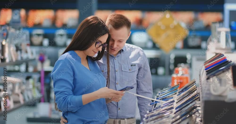 Happy couple looking at a new digital camera at an electronics shop