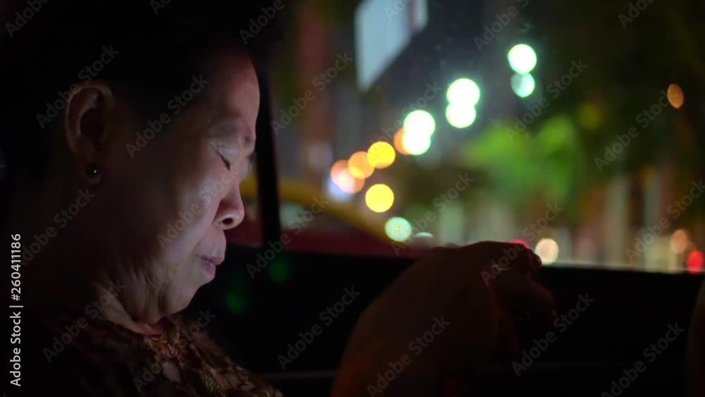 Asian senior woman use smartphone in car at night addict to technology Asian senior woman use smartphone in car at night addict to technology