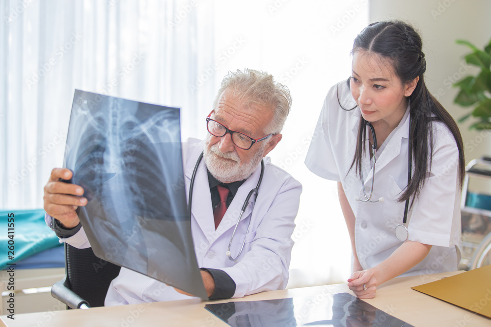Senior male doctor is giving women doctor visiting radiologist for x-ray exam. Senior male doctor is giving women doctor visiting radiologist for x-ray exam.