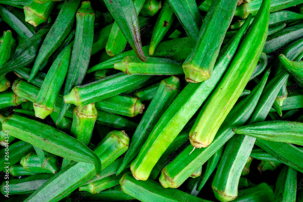 Obraz premium Pile of fresh green okra displayed at a greengrocer in a farmer's market in Chiang Mai, Thailand.