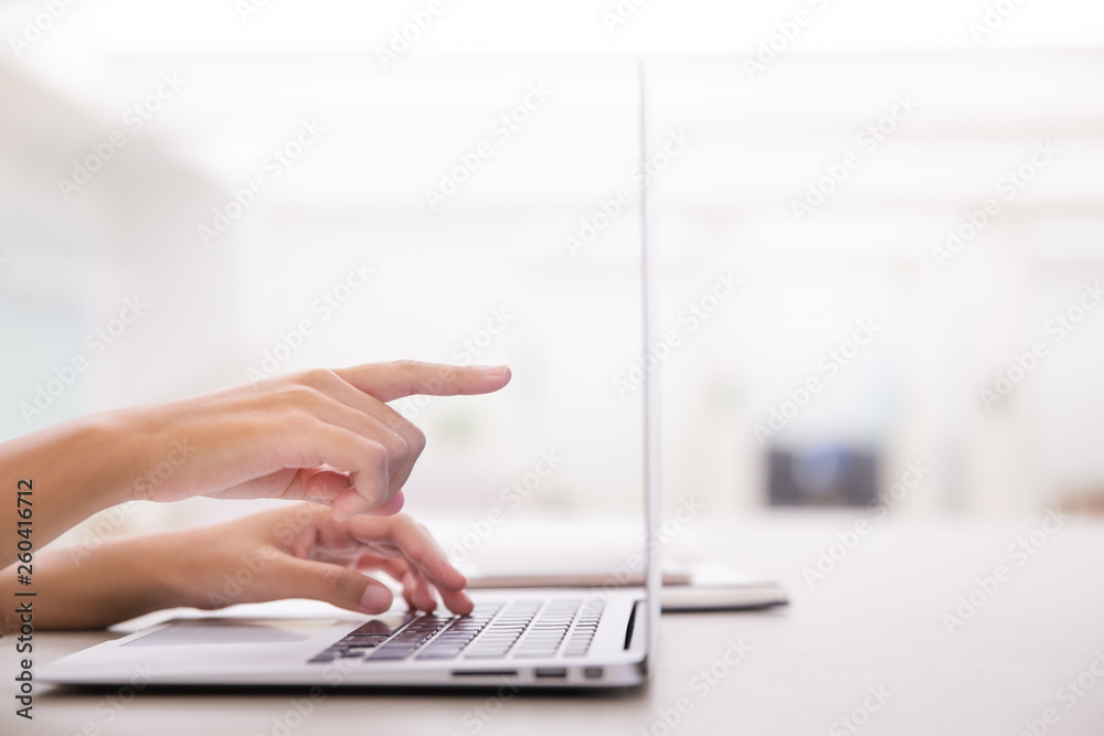 Close up of young female hands using laptop and pointing the screen in modern office or loft near by the window.