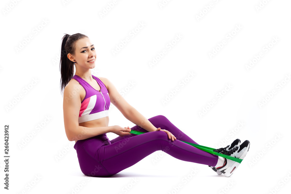 Sporty woman does exercises and stretch on legs with sport fitness rubber bands on white background. Photo of muscular woman in sportswear on white background. Strength and motivation. Sporty woman does exercises and stretch on legs with sport fitness rubber bands on white background. Photo of muscular woman in sportswear on white background. Strength and motivation.