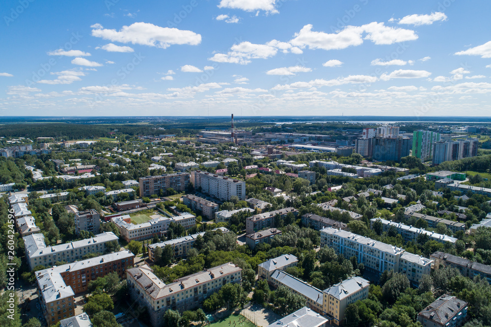 Top down aerial drone image of a Ekaterinburg with low houses and new high-rise buildings. Midst of summer, backyard turf grass and trees lush green.